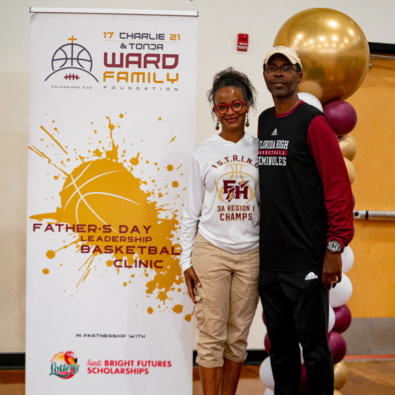 Charlie and Tonja Ward in front of the Father's Day Leadership Basketball Clinic banner